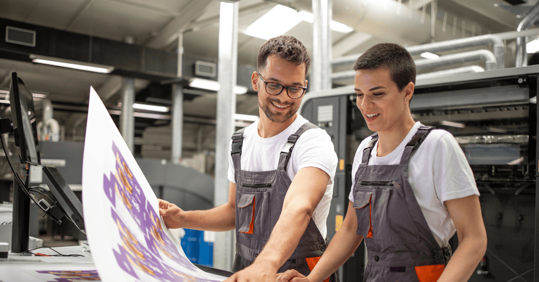 graphic designers with paper on industrial printer