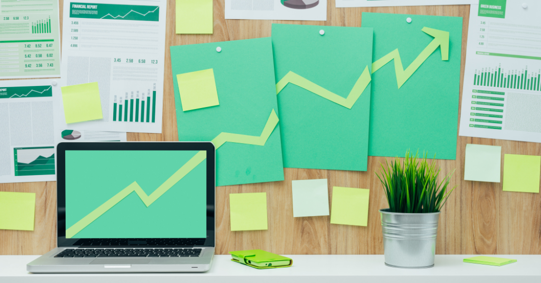a laptop on a desk surrounded by green paper materials